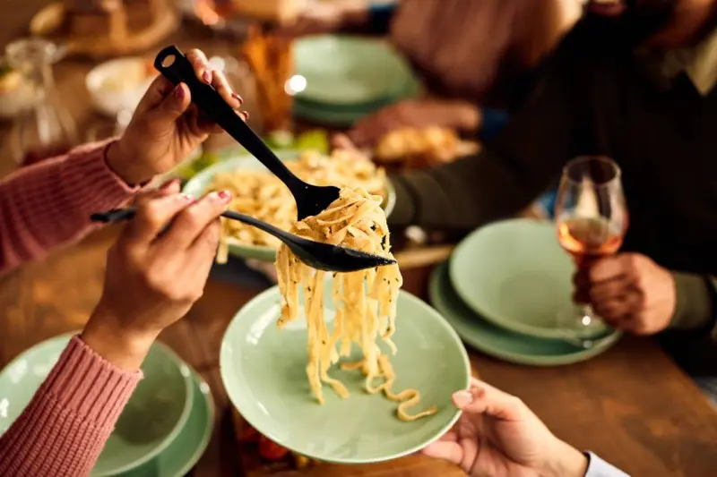 close up of people having pasta for lunch at dinin
