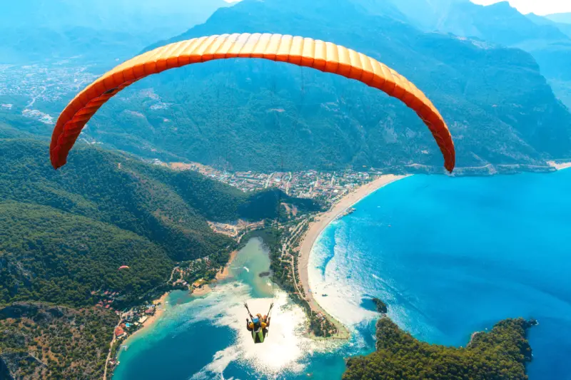 Paraglider tandem flying over the sea with blue water